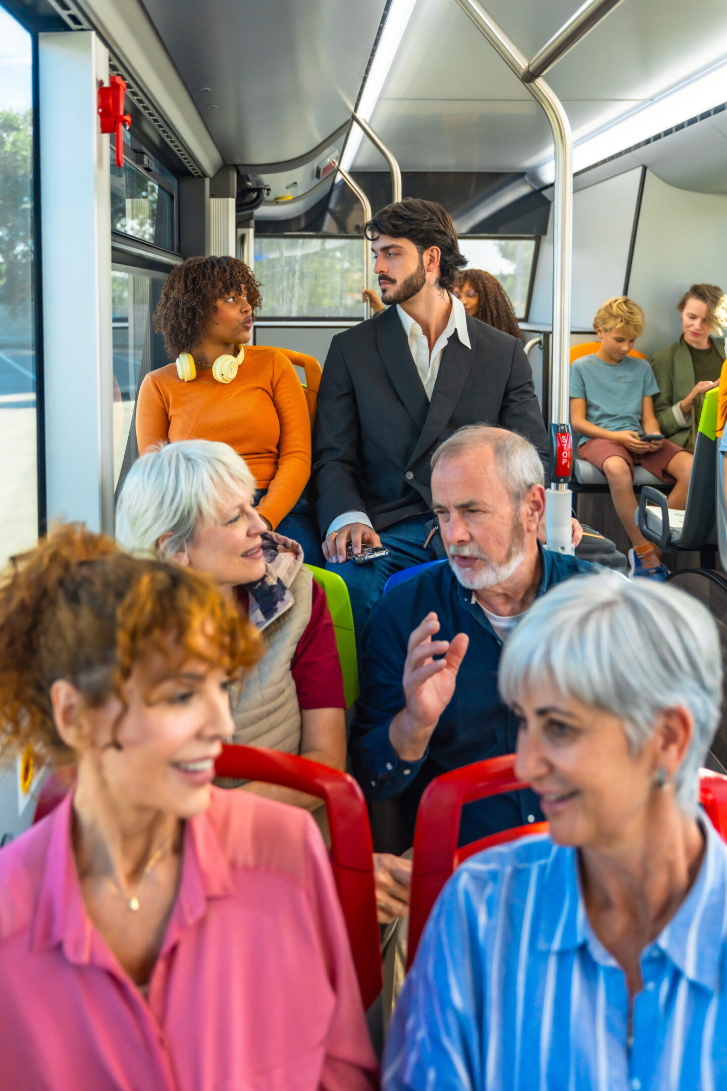 People seated and talking on a bus.