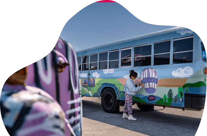 Child painting colorful school bus mural.